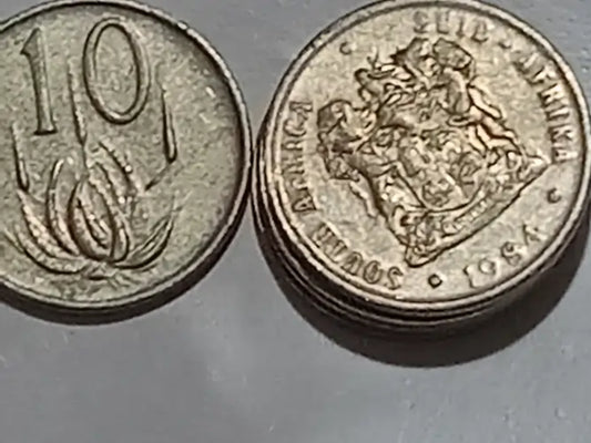 Two 10 cent coins, one showing the denomination '10'' and the other with a coat of arms, on a gray background.