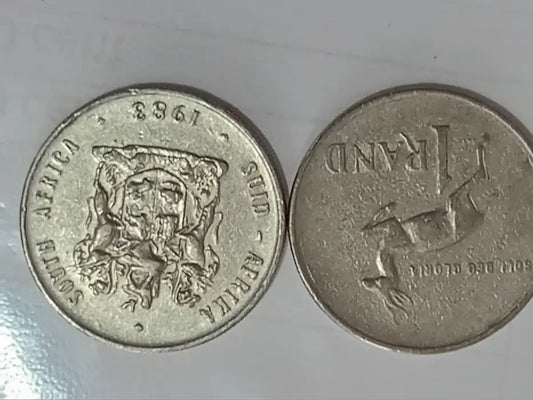 Two 1983, R1 coins with coat of arms  + springbok design on a grey background