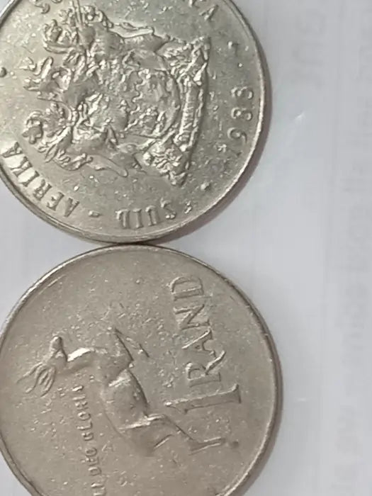 Two 1988, R1 coins with Obverse: Coat of arms of South Africa
Reverse: Springbok, denomination below, date above on a white background