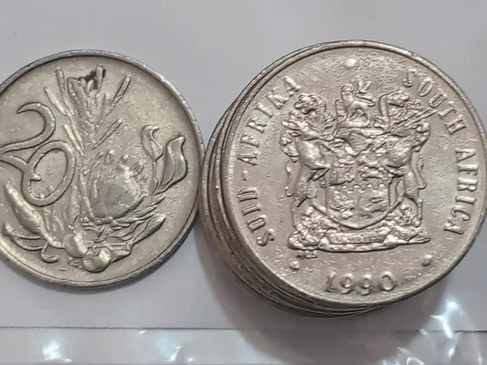 Two 1990 20 cent coins from South Africa on a reflective surface