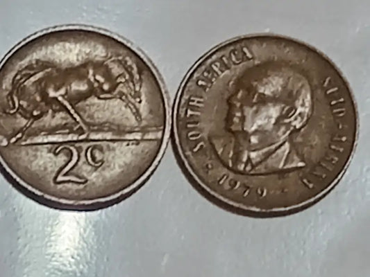 Two 1979 2 Cent (Presidential) series South African coins on a reflective surface