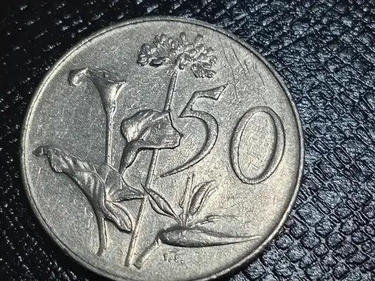 1990, 50 cent coin with Protea flower and 50 cent denomination design on a textured black surface