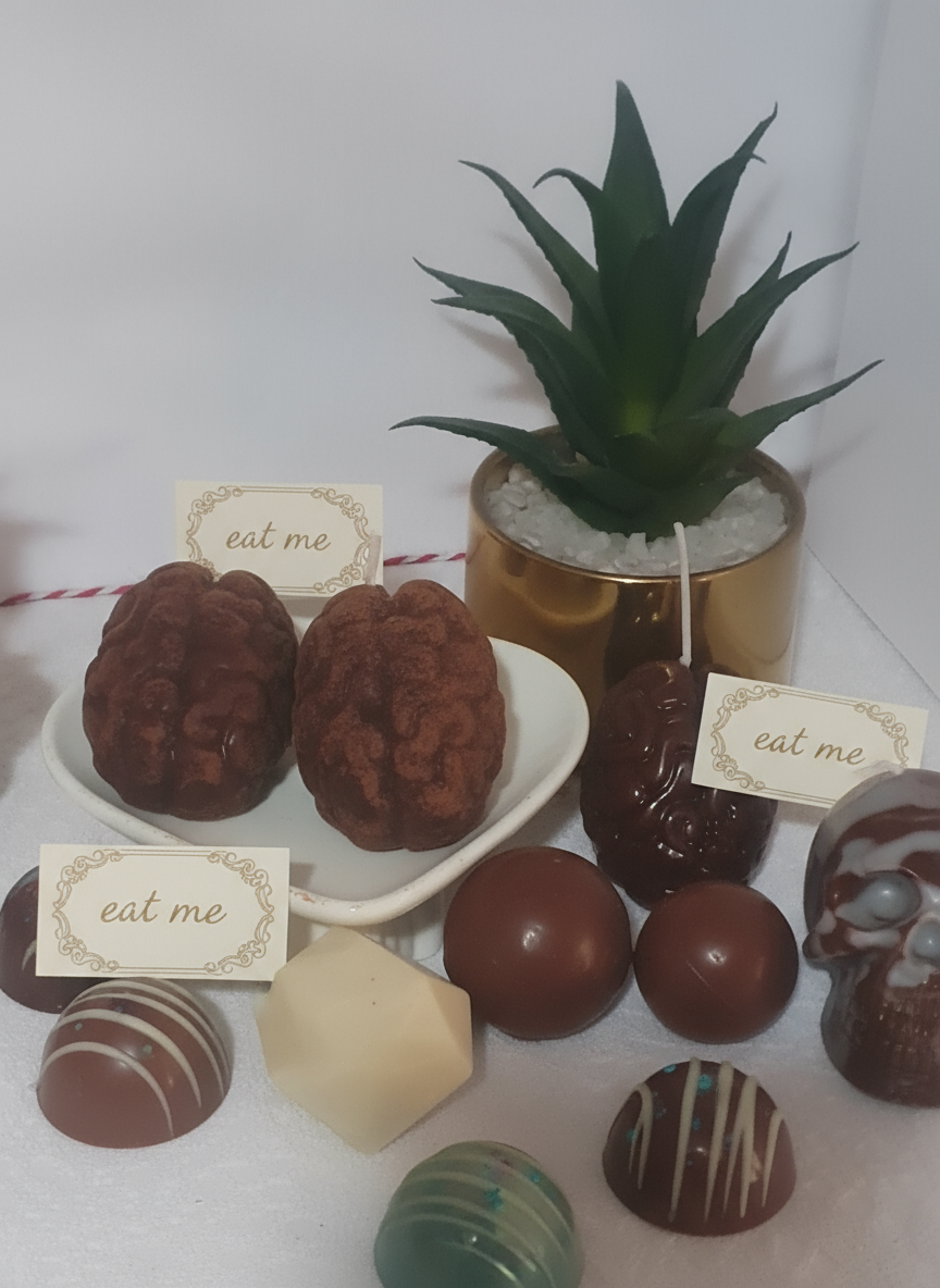 Candle-shaped objects resembling brains on a white surface with a plant in the background.