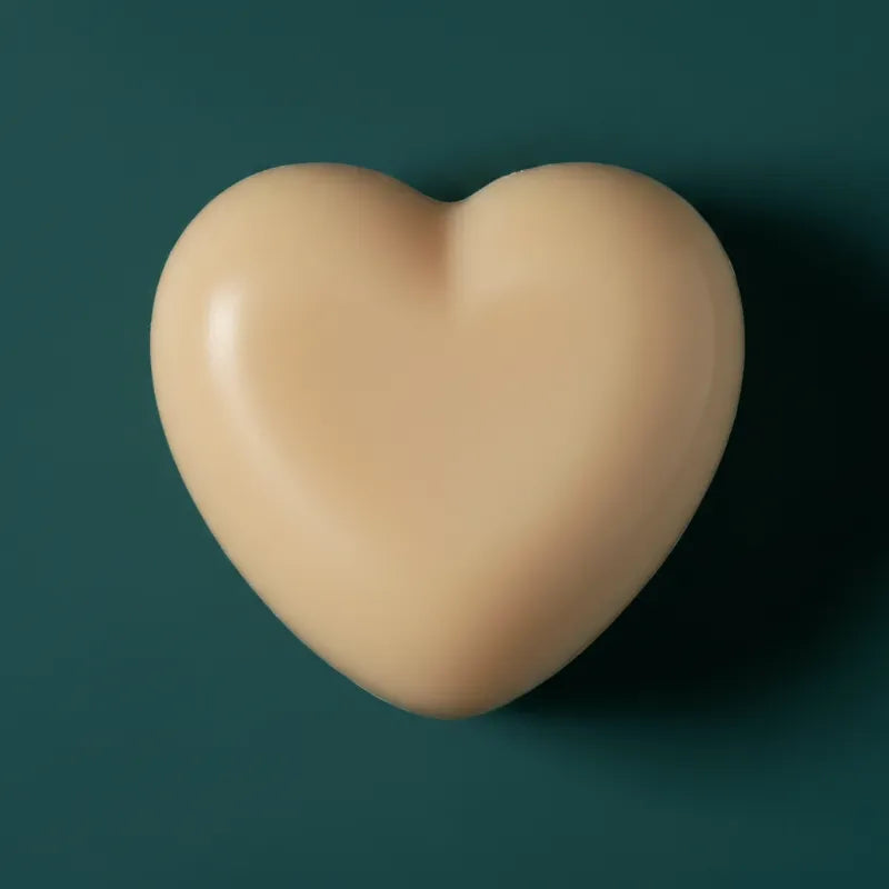 Beige heart-shaped wax candle on dark teal background – LAVA Heart Candle