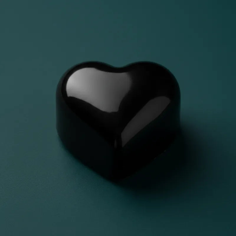 Black heart-shaped wax candle on dark teal background – LAVA Heart Candle