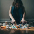 Person sorting through a large number of prescription bottles on floor