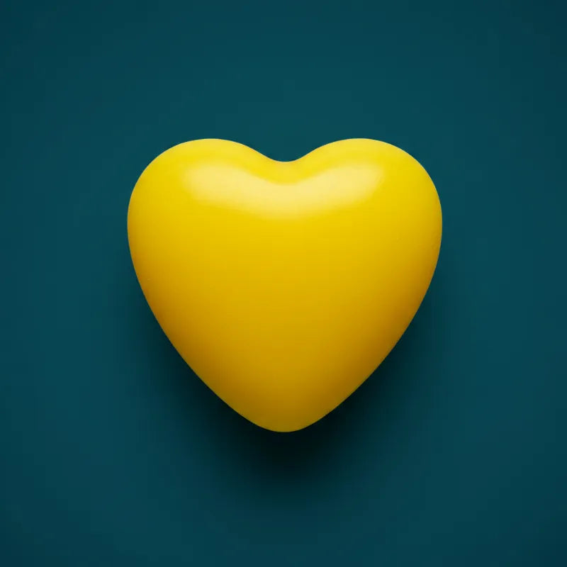Yellow heart-shaped wax candle on dark teal background – LAVA Heart Candle